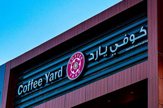 لافتة كوفي يارد المضيئة بالعربية والإنجليزية على واجهة المقهى